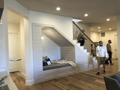 two men are standing in the living room looking at something on the wall behind them