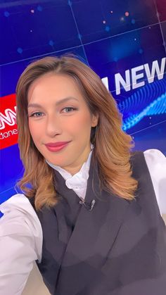 a woman is posing for the camera in front of a news desk