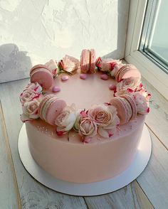 a pink cake decorated with roses and macaroons