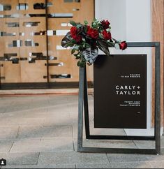 a black and white sign with red flowers on it in front of a wooden door