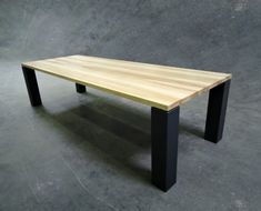 a wooden table sitting on top of a cement floor next to a black metal frame