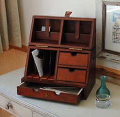 an old wooden desk with two drawers and a vase on the table next to it