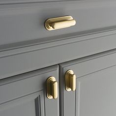 a close up view of the handles on a gray cabinet with gold hardware and knobs