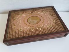 an old wooden box with gold coins in the center and a woman's face on it