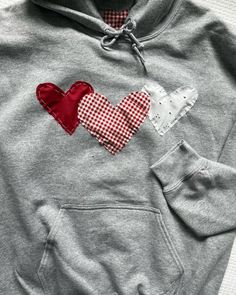 a red and white checkered heart on a gray hoodie with two hearts embroidered on the chest