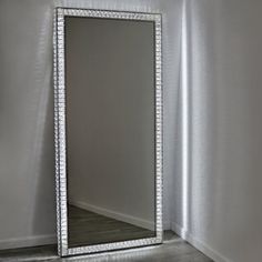 a mirror sitting on top of a floor next to a white wall in a room