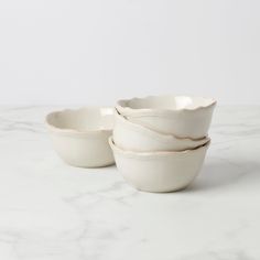 three white bowls sitting on top of a marble counter