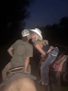 a man and woman riding on the back of an elephant in the dark at night