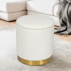 a white and gold ottoman sitting on top of a rug in a living room next to a couch