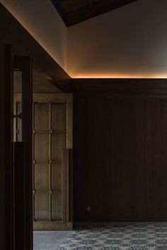 an empty room with wooden walls and tile flooring is lit by recessed lighting