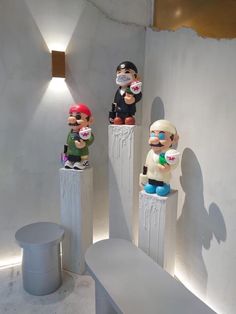 three small sculptures are sitting on pedestals in the middle of a room with white walls