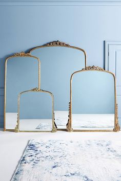 three mirrors sitting next to each other on top of a white rug in front of a blue wall