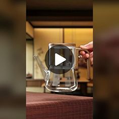 a video demonstrating how to pour water into a glass teapot with a lid and handle