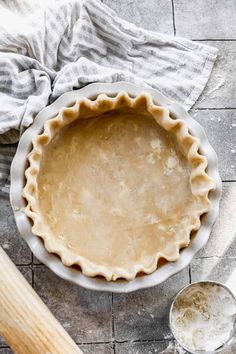 an uncooked pie crust in a bowl next to a rolling pin