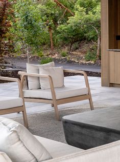 two chairs and a table on a patio with trees in the background