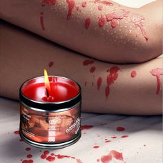 a candle with blood all over it sitting next to a woman's legs and body