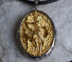 a gold and silver pendant with an image of a woman on it