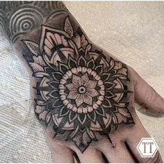 a person's hand with a black and white tattoo design on the middle of it