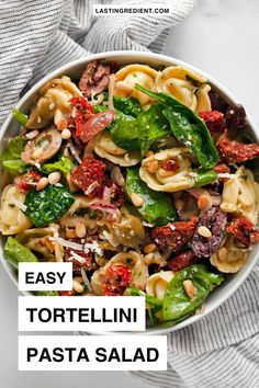 a white bowl filled with pasta and spinach salad on top of a gray towel