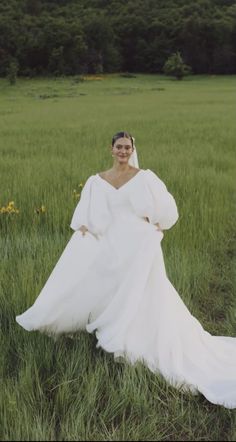 a woman in a white dress is standing in the grass