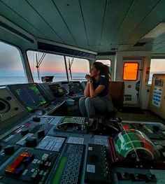 a woman sitting on the deck of a boat talking on her cell phone while looking out at the ocean