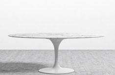 an oval marble table with white pedestals on the top, against a plain wall