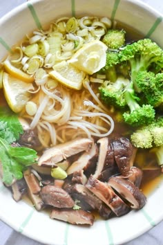 a white bowl filled with noodles, mushrooms and broccoli on top of a table