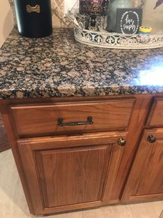 a kitchen counter with granite top and wooden cabinetry in the middle, next to an ice bucket