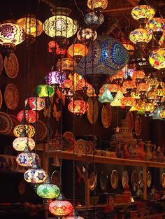 many colorful lights hanging from the ceiling in a room filled with plates and vases