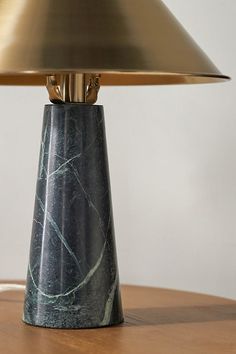 a marble lamp on a wooden table with a gold shade