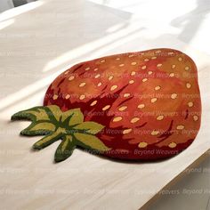 a strawberry shaped pillow sitting on top of a wooden table