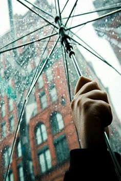 a person holding an open umbrella in the rain