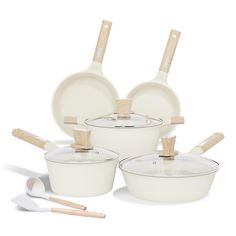 a set of white pots and pans with wooden spoons next to them on a white background