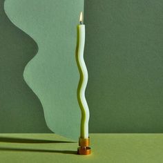 a lit candle sitting on top of a green table next to a piece of paper