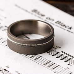 A great choice for the musician groom who plays guitar, this sandblasted titanium wedding band has a nickel guitar string. You can customize this ring with differentcolors of strings (or send us your own string) to make this guitar string wedding band more unique to you and your love of music.RING LAYOUT -Guitar String Ring for Musicians-3862 Ring Width: 8 mm Ring Sleeve:Titanium Ring Profile: Flat Ring Finish: Sandblasted2 mm Titanium 1.25 mm Guitar String 4.75 mm TitaniumRING FITTING:We highly Guitar String Ring, Music Ring, String Ring, Rock N Roll Wedding, Titanium Wedding Band, Titanium Ring, Matching Wedding Bands, Unique Wedding Bands, Titanium Rings