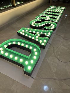 two large neon signs sitting on top of a tile floor in front of a window