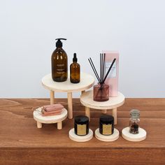 three tables with soaps, lotion bottles and candles on them sitting on a wooden table