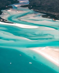 an aerial view of white sand and blue water in the ocean with boats on it