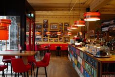 the interior of a restaurant with red chairs and bookshelves on either side of the bar