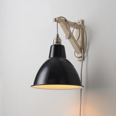 a black and white light hanging from the side of a wall next to a lamp