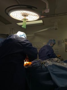 two surgeons are performing surgery in an operating room with lights on and equipment hanging from the ceiling