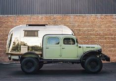 an old green truck parked in front of a brick building