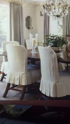 a dining room table with white chairs and a chandelier hanging from the ceiling