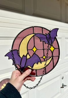 a hand holding a stained glass bat hanging from a hook in front of a garage door