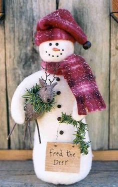 a snowman with a red hat and scarf holding a sign that says feed the deer