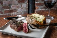 steak and potatoes on a plate with a glass of wine