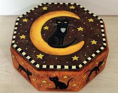 a decorative box with a black cat sitting on the moon