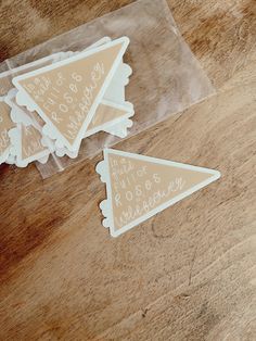 three clear stickers with words on them sitting on a wooden table next to a pair of scissors