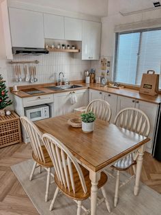 a kitchen with white cabinets and wooden table surrounded by four chairs in front of the sink