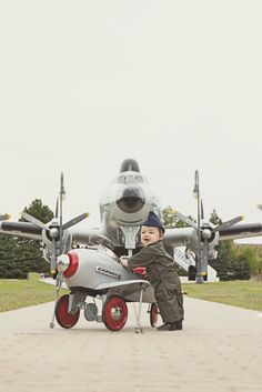 a young boy playing with a toy airplane on the tarmac next to an airplane